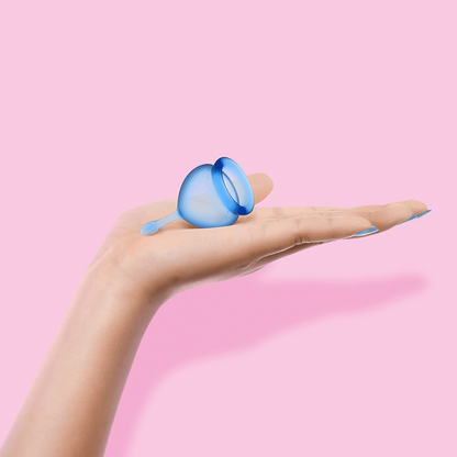 Maža menstruacinė taurelė laikoma delne – parodytas dydis ir forma